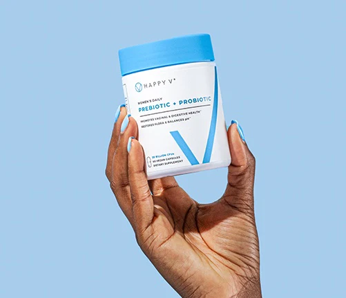 Happy V prebiotic and probiotic bottle held in a hand against a blue background.