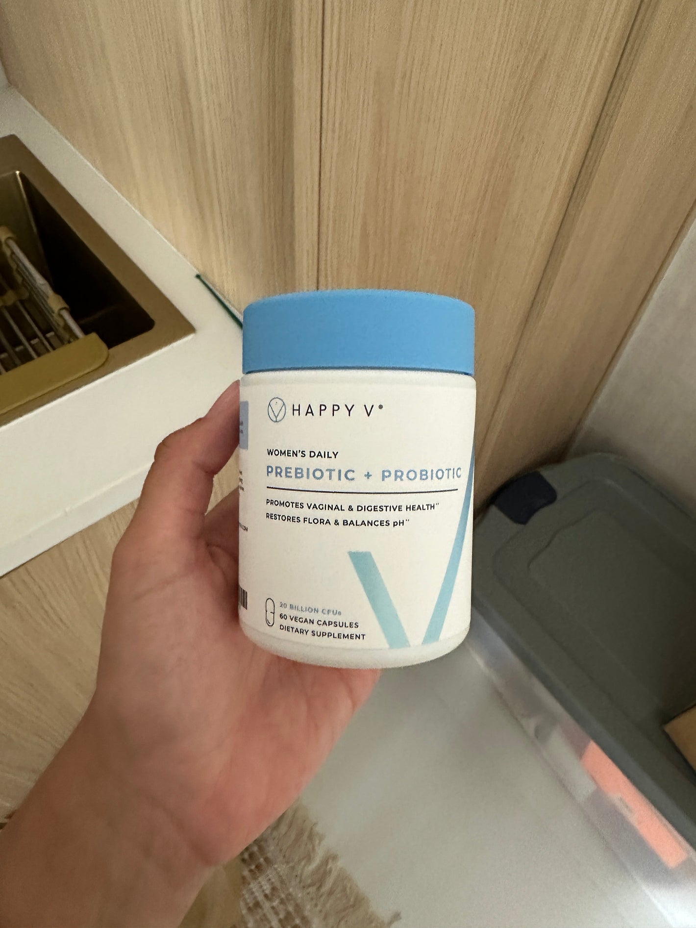 Hand holding Happy V Prebiotic + Probiotic bottle, showcasing clean packaging for feminine wellness.
